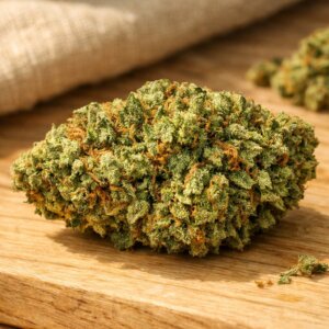 Fleur séchée Amnesia CBD aux teintes dorées et vertes sur fond en bois clair et lin